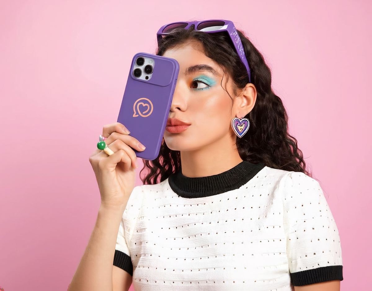 Woman holding up a phone with a heart-logo case, checking her messages